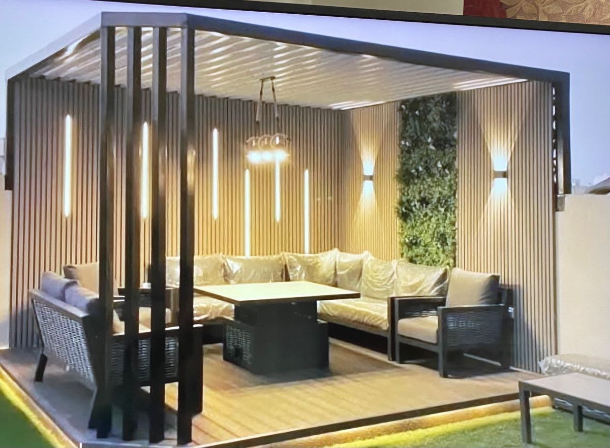 خدمة جلسة خشبية بإضاءة دافئة ضمن قسم حدائق وبناء مجالس خارجية